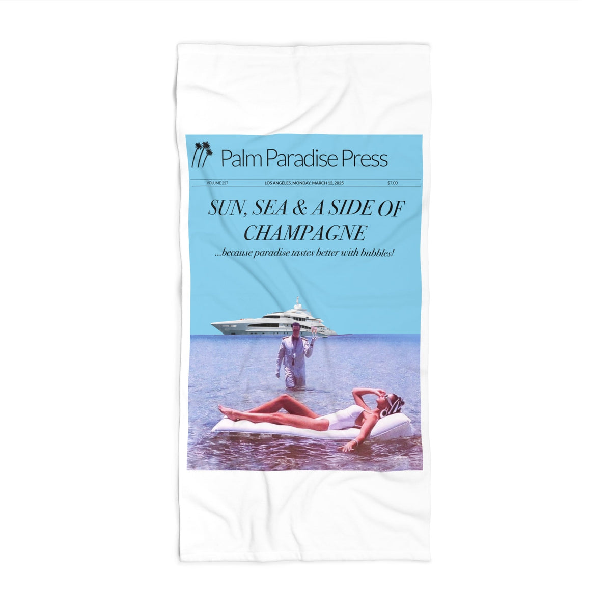 A white rectangular beach towel featuring a printed cover-style design with a light blue vertical panel on the left, the text 'Palm Paradise Press' and 'SUN, SEA & A SIDE OF CHAMPAGNE', and a photographic scene of a woman lounging on a beach with a yacht.