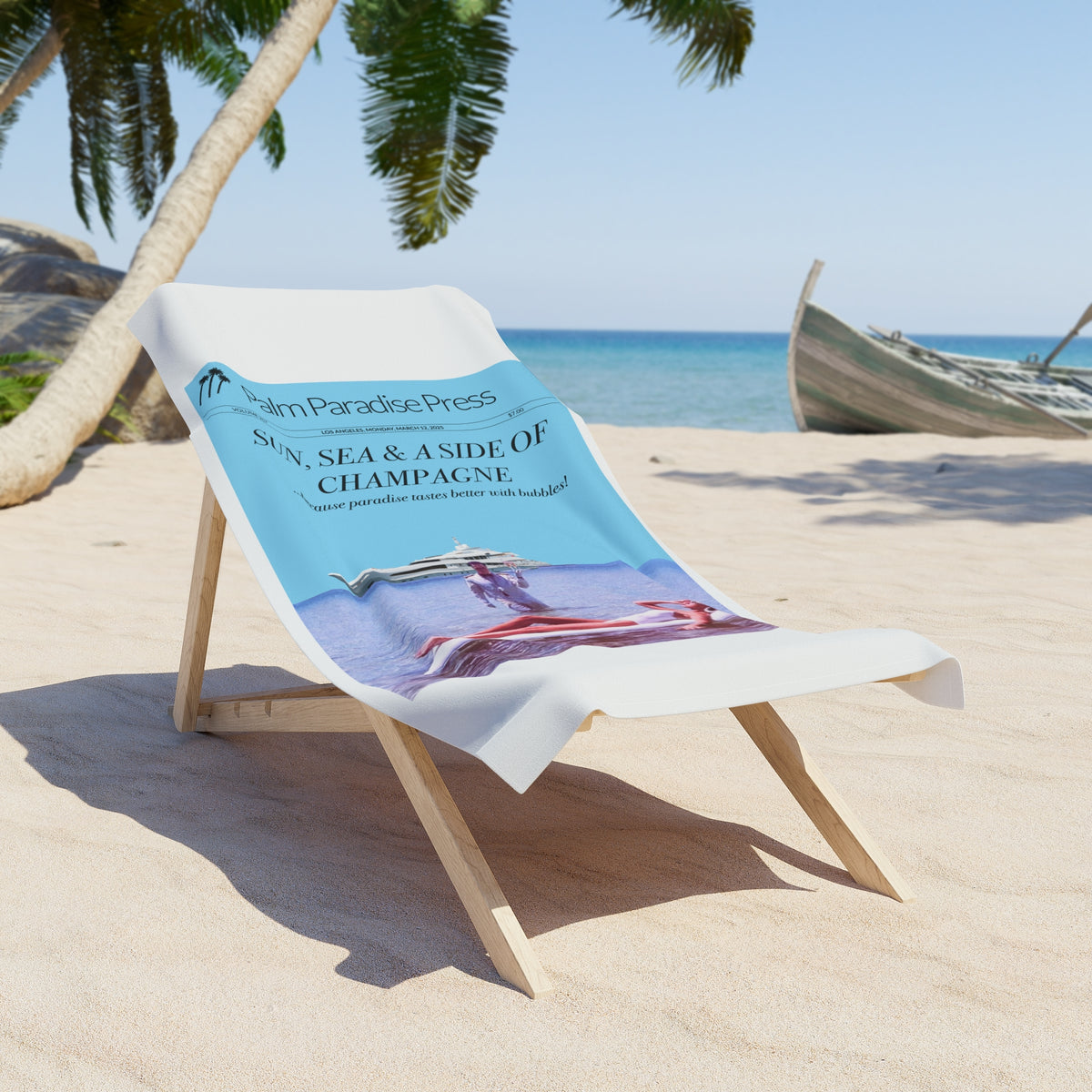 A white beach towel draped over a wooden lounge chair on a sandy beach, featuring a printed design with the text 'SUN, SEA & A SIDE OF CHAMPAGNE' and 'Palm Paradise Press'.
