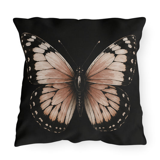 A square black throw pillow featuring a large, detailed butterfly graphic printed on the front. The butterfly has wings in shades of dusty pink, beige, and brown with black borders and small white spots.