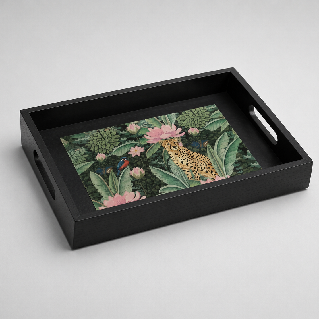 A rectangular black serving tray with cutout handles, featuring a colorful tropical print of a leopard, pink lotus flowers, and green foliage on a light gray background.