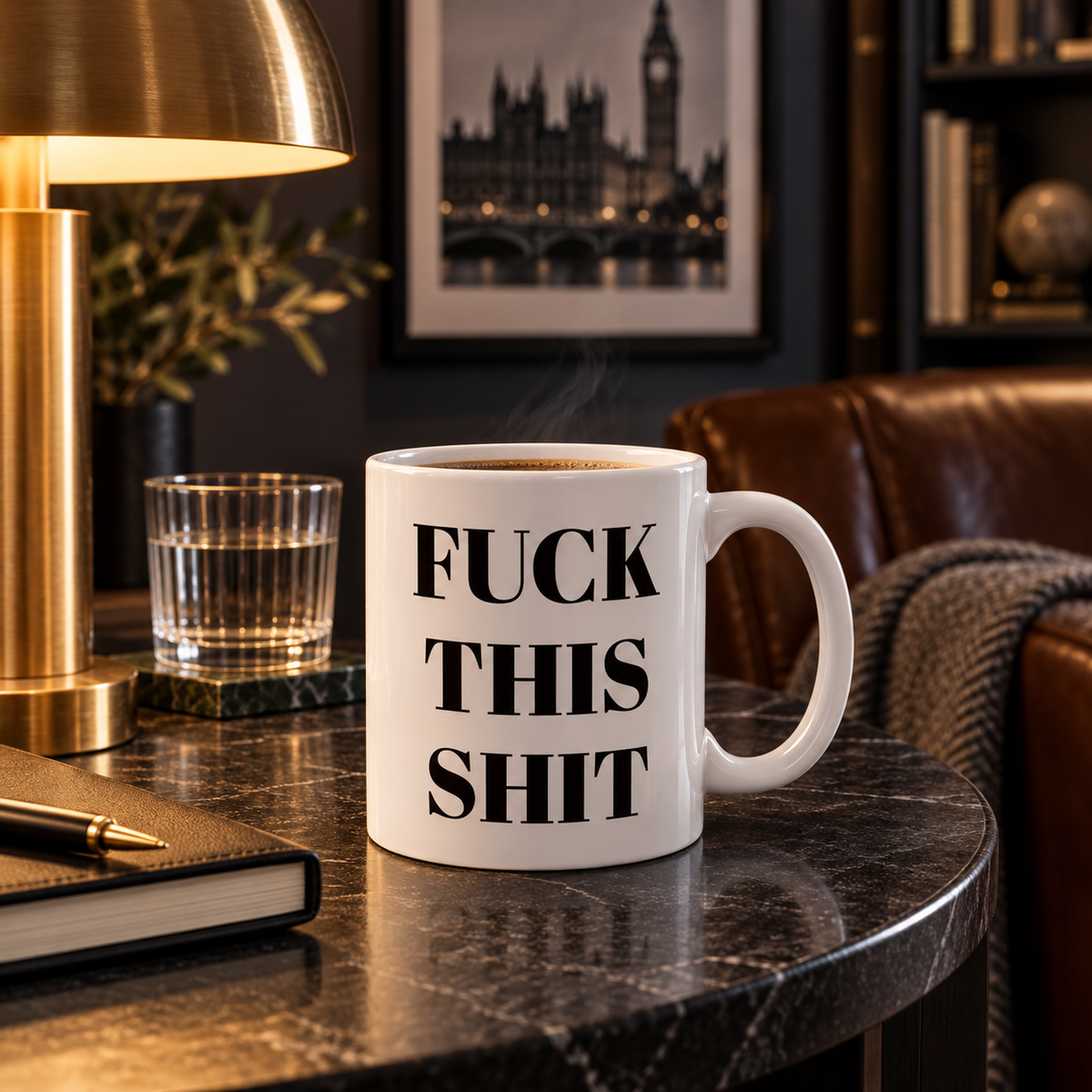 A white ceramic funny swear words coffee mug with black serif typography sits on a dark marble table in a cozy, dimly lit room with a brass lamp, glass, notebook, and leather chair in the background.