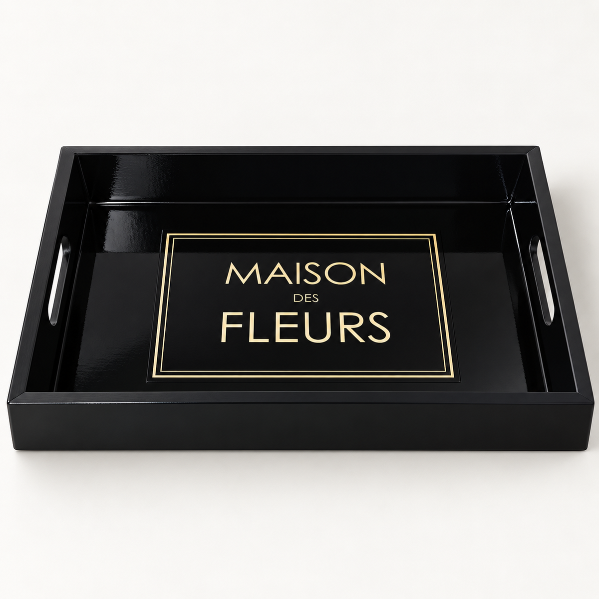 A black rectangular serving tray with side handles and a glossy finish, featuring a gold-bordered label that reads 'MAISON DES FLEURS' in gold lettering in the centre.