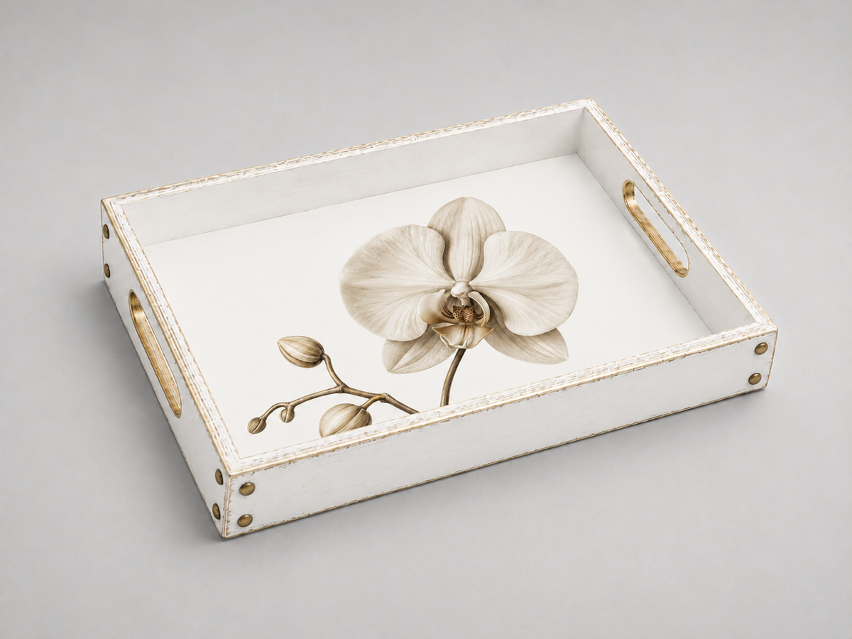 A rectangular white serving tray with gold-toned metal handles and corner hardware, featuring a large beige orchid flower and small buds printed on the inner surface, shown on a light gray background.