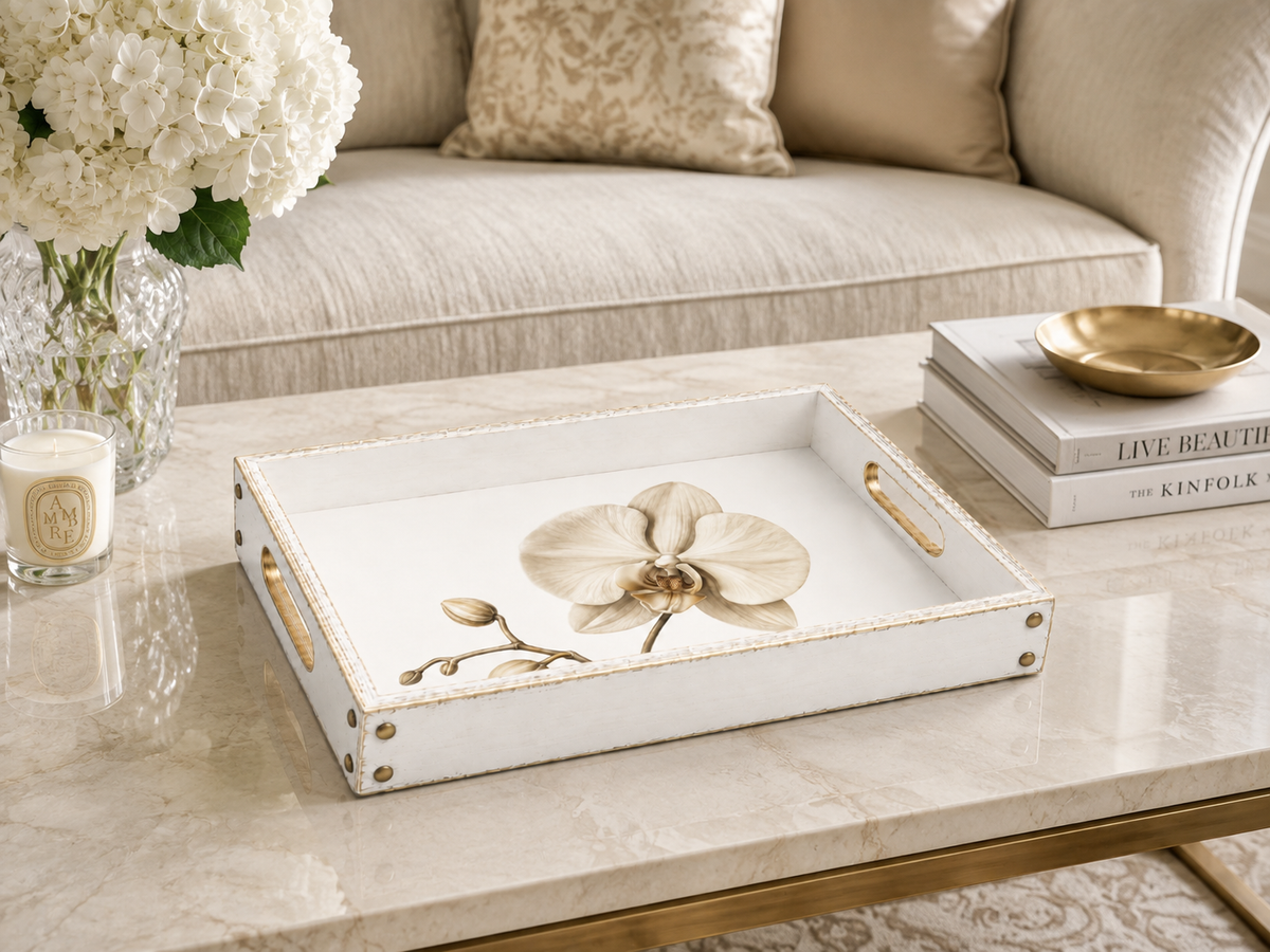A white and gold rimmed, distressed tray, with a white orchid design in the centre. 