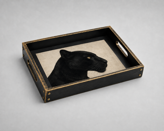A rectangular black serving tray with gold-toned metal trim and handles, featuring a black panther head mounted on a beige background insert, photographed on a light gray studio surface.