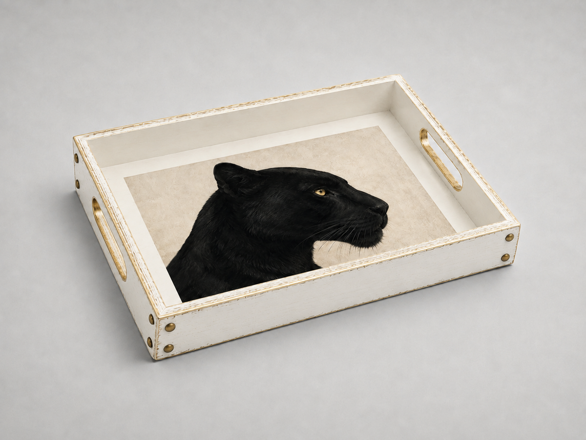 A rectangular white serving tray with gold-toned handles and corner hardware, featuring a printed or inlaid black panther portrait on a light beige background, photographed on a smooth light gray surface.