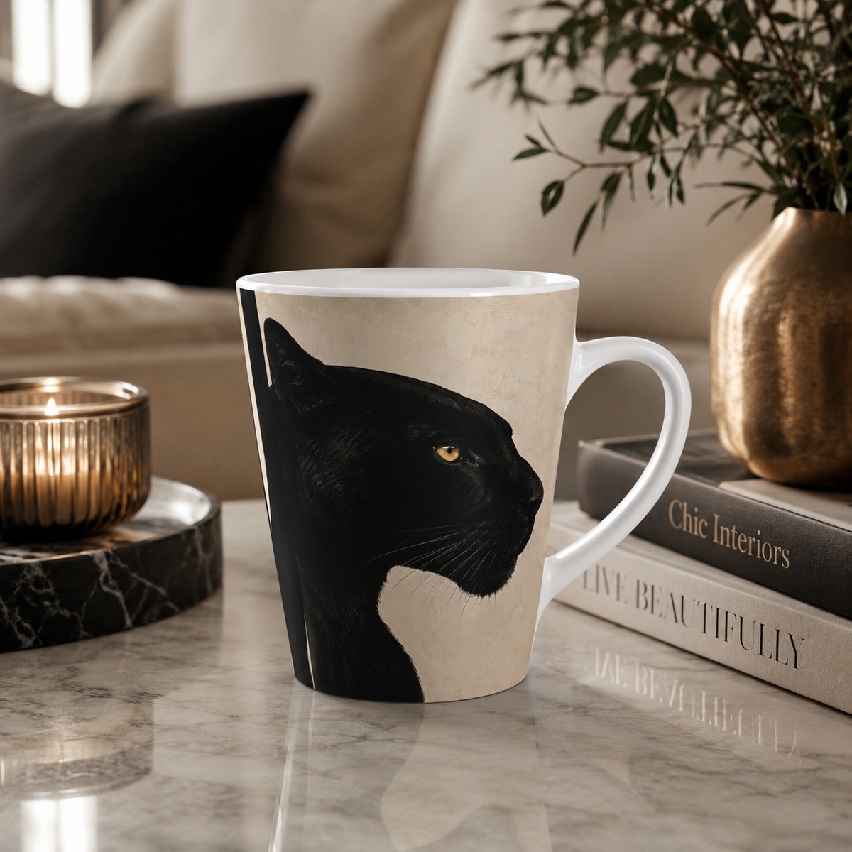 A black panther design on a mug on a marble tabletop with a lit candle and interior design books.