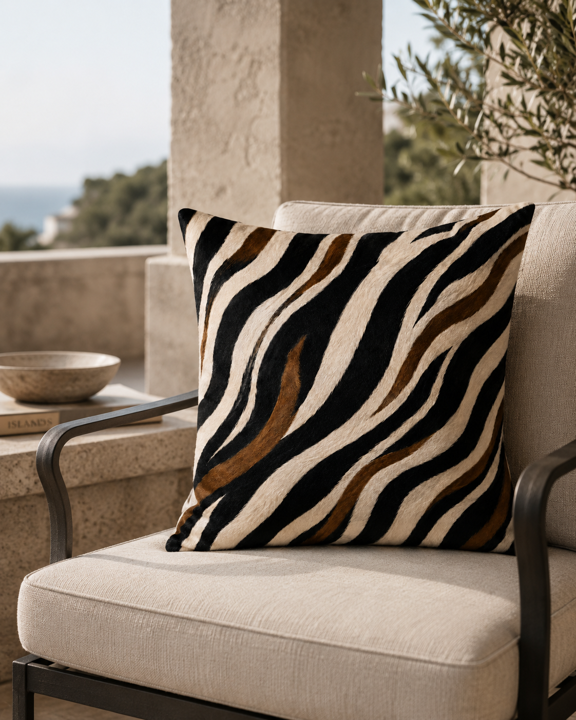 A square throw pillow with a zebra-stripe pattern in black, cream, and brown, resting on a beige outdoor patio chair.